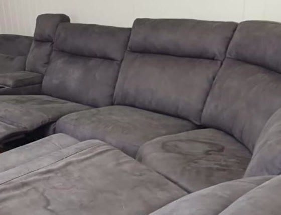 Gray reclining sectional sofa with a visible watermark stain on the cushion before upholstery cleaning
